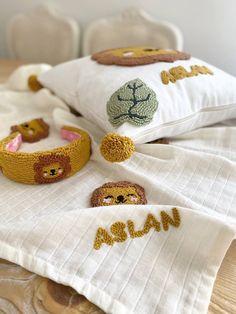 three pillows with embroidered animals on them sitting on a bed