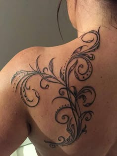 the back of a woman's shoulder with an artistic tattoo design on her left side