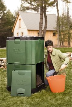 a woman kneeling down next to a green trash can