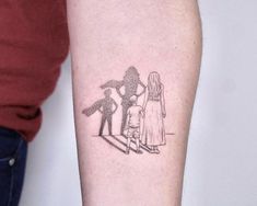 a small tattoo on the arm of a person with a little boy and girl standing next to each other