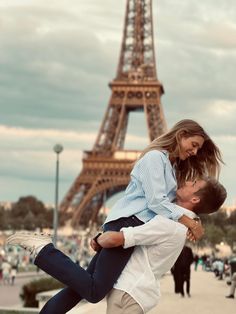 a man carrying a woman in front of the eiffel tower