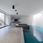 an indoor swimming pool in the middle of a living room with stairs leading up to it