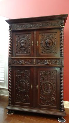 an old wooden cabinet with ornate carvings on the front and sides, against a red wall