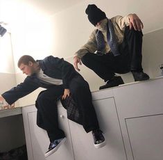 two young men sitting on top of white cabinets