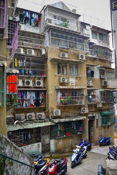 several scooters parked in front of an apartment building with multiple balconies