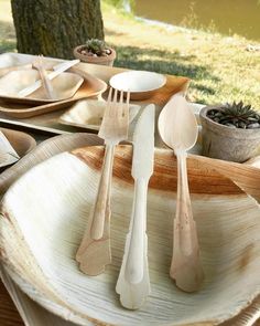 wooden utensils are sitting on top of white plates in front of a tree