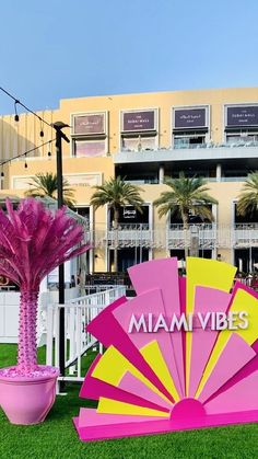 a pink and yellow umbrella next to a potted plant in front of a building