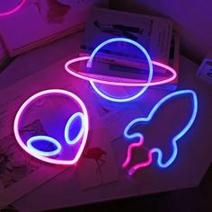 two neon lights sitting on top of a table next to an open book and pen