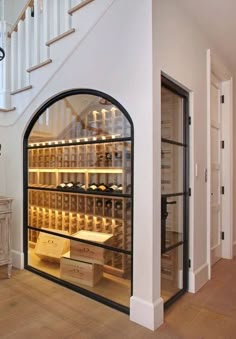 a wine cellar in the corner of a room with stairs leading up to an upstairs stair case