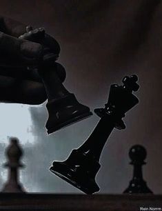 a hand holding a chess piece over a black and white photo