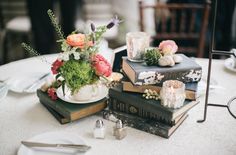 a table topped with books and flowers on top of each other next to a candle