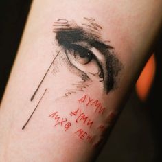 a close up of a person's eye with writing on the side of their arm