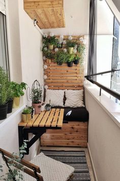 a small balcony with plants and potted plants on the wall, along with a bench made out of pallets