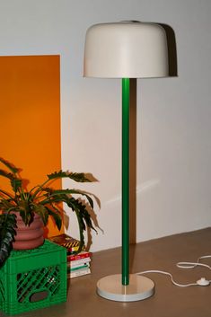 a green lamp sitting on top of a table next to a potted plant