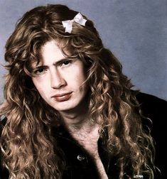 a man with long curly hair wearing a black shirt and white bow in his hair