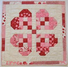 a piece of quilted material with red and white squares in the shape of hearts