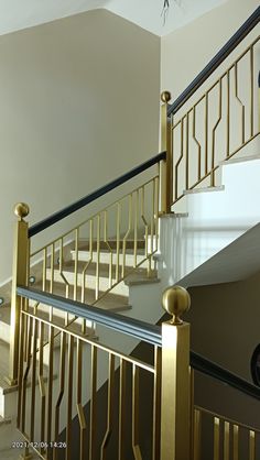 there is a stair case in the middle of this room with white walls and gold railings