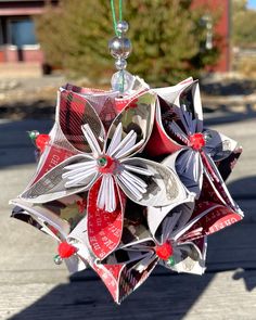 a christmas ornament hanging from a string on a street corner with trees in the background