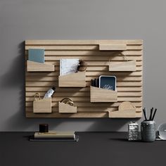 a wooden shelf with various items on it and a cup next to it, in front of a gray wall