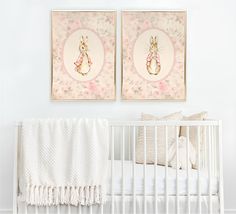 two framed pictures hang above a crib in a baby's room with pink and white decor