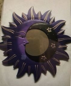 a purple sun and moon shaped mirror sitting on top of a table