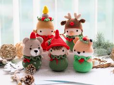 crocheted stuffed animals dressed up in christmas outfits with pine cones and decorations around them