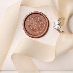 a close up of a wax seal with a diamond ring on it next to some white fabric