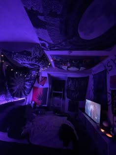 a bedroom with purple lighting and decorations on the ceiling