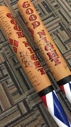 two baseball bats sitting on top of a carpet next to each other with writing on them