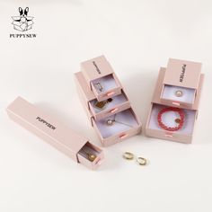 three pink jewelry boxes with rings and bracelets in them