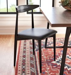 two black chairs sitting on top of a rug next to a table with a potted plant