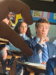 a group of young people sitting at desks in front of a mirror with their hands on their chins