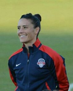 a female soccer player smiles as she stands on the field