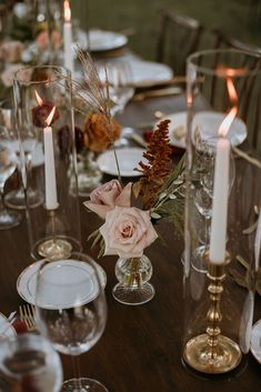 the table is set with candles, plates and flowers