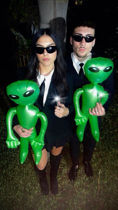 two people dressed up as aliens holding balloons