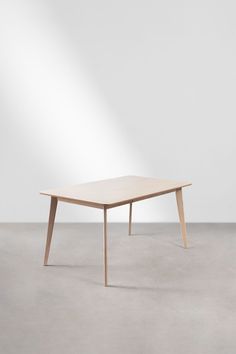 a wooden table sitting on top of a cement floor next to a white wall in an empty room