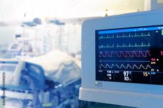 an image of medical equipment in a hospital setting with monitors on the wall and patient's bed in the background