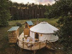 a yurt in the middle of a forest with trees around it and a deck