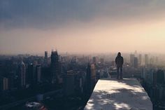 a person standing on top of a tall building in the middle of a large city