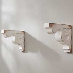 two white wooden brackets are on the wall