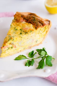 a slice of quiche on a white plate with parsley garnishes