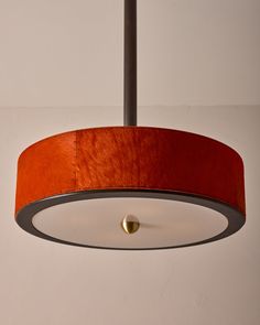 a light that is hanging from the ceiling with a red shade on it's side