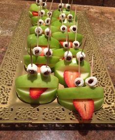 some food that is on a tray with strawberries and eyeballs in the shape of frogs