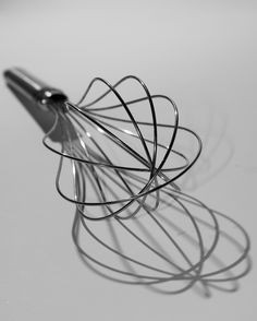 a metal wire whisk on a white table