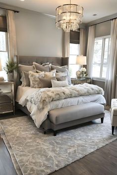 a large bed sitting in a bedroom next to two lamps and a chandelier