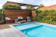 a small pool in the middle of a backyard with lounge chairs and a wooden fence