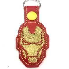 a red iron man keychain with a yellow button on the front and back