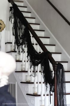 the stairs are decorated with black ribbons and candles for halloween decorations on display at the bottom of the staircase