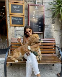 a woman sitting on a bench with her dog and ice cream in front of her