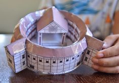 someone is making a paper house out of toilet paper on the table with their hands